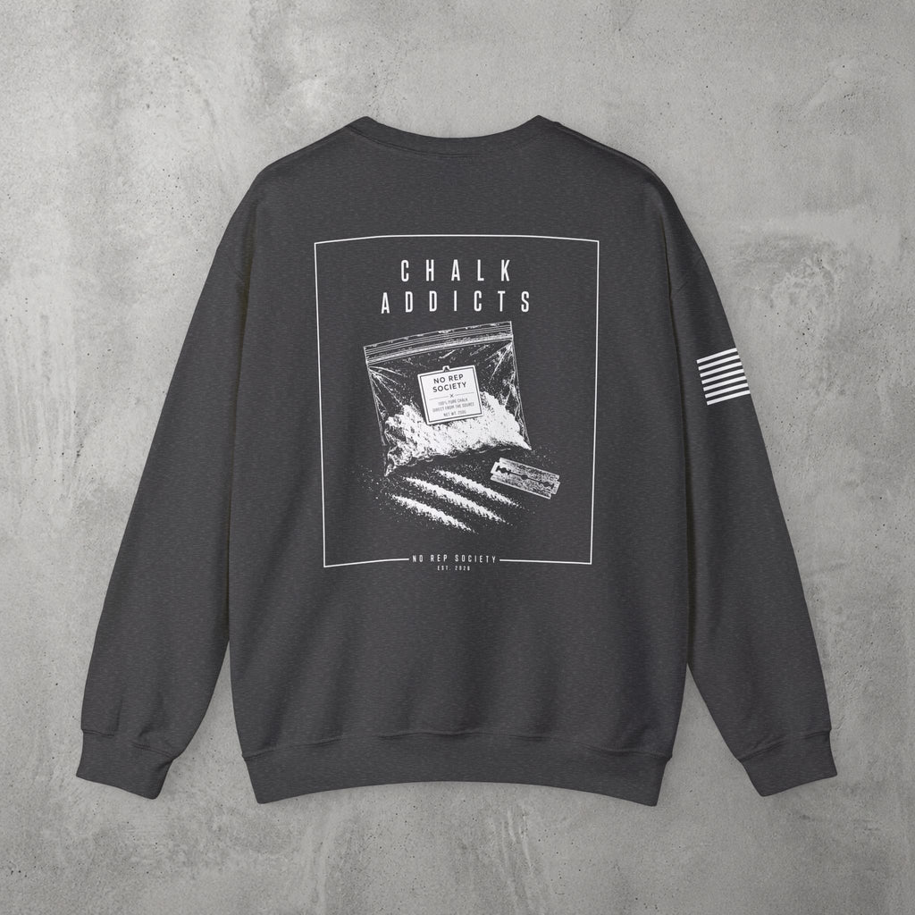 Dark Heather Chalk Addicts Crewneck by The No Rep Society, flat lay on grey concrete, back print of an open bag of gym chalk spilling across a bordered frame under CHALK ADDICTS lettering.