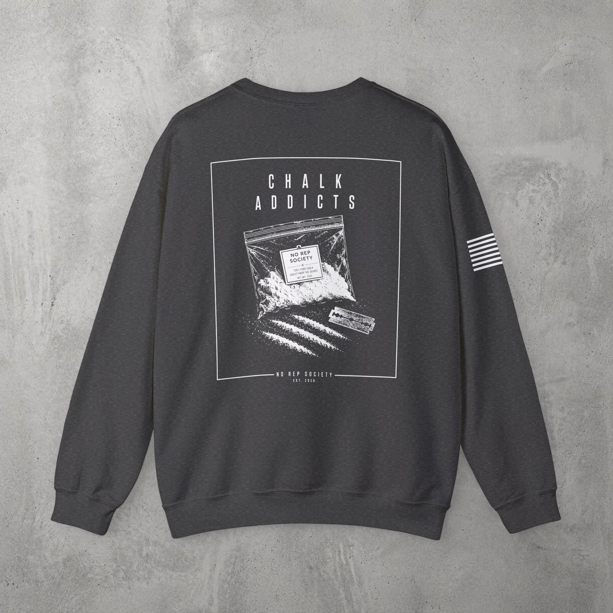 Dark Heather Chalk Addicts Crewneck by The No Rep Society, flat lay on grey concrete, back print of an open bag of gym chalk spilling across a bordered frame under CHALK ADDICTS lettering.