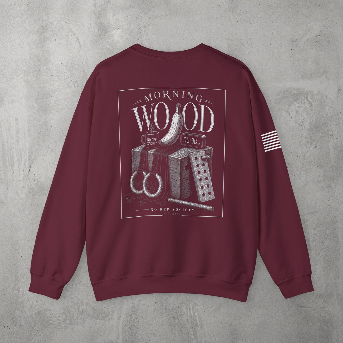Maroon Morning Wood Crewneck by The No Rep Society, flat lay on grey concrete, back print of a banana, gymnastic rings and a wooden plyo box under MORNING WOOD lettering.