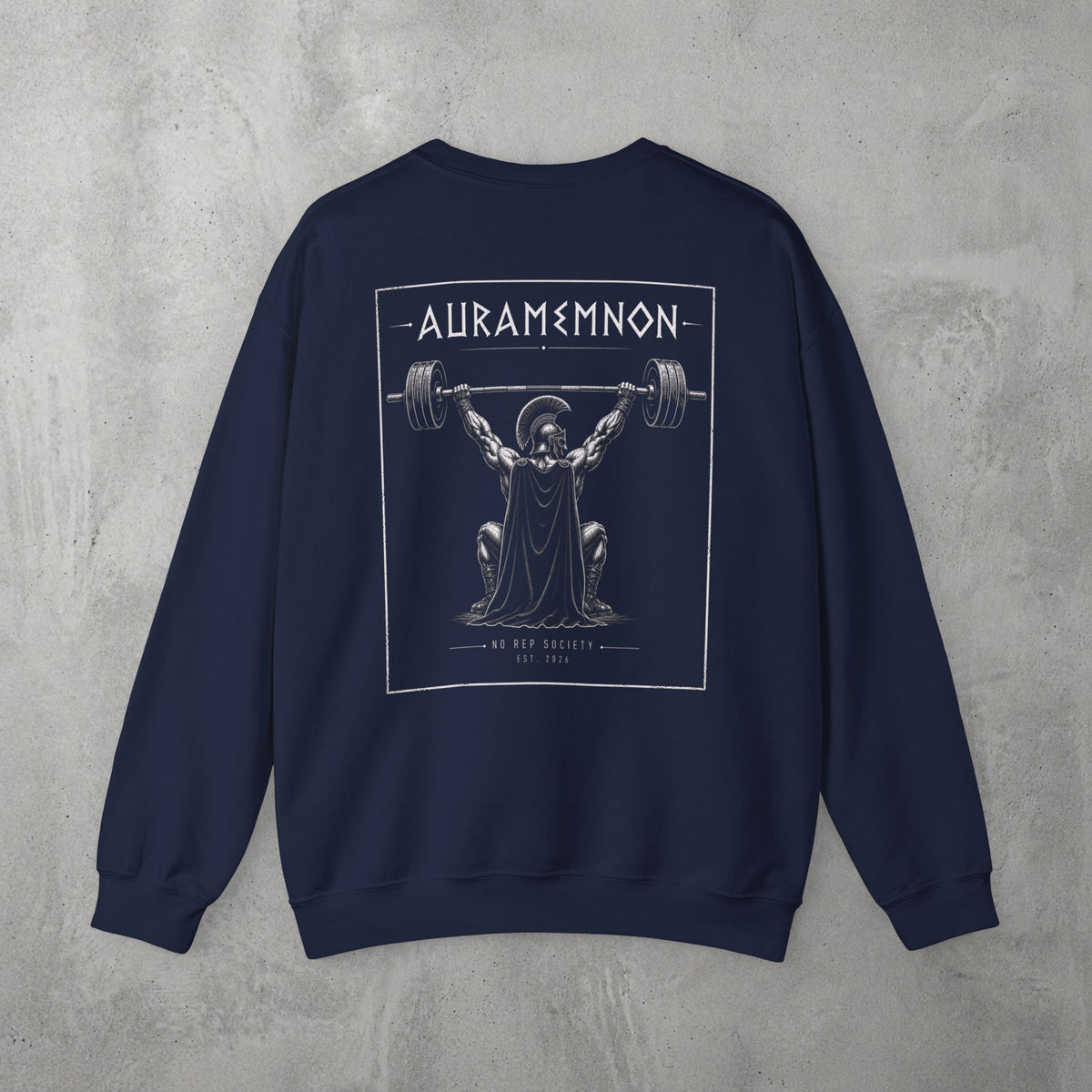 Navy Auramemnon Crewneck by The No Rep Society, flat lay on grey concrete, back print of a caped warrior in a plumed helmet pressing a loaded barbell overhead under AURAMEMNON lettering.