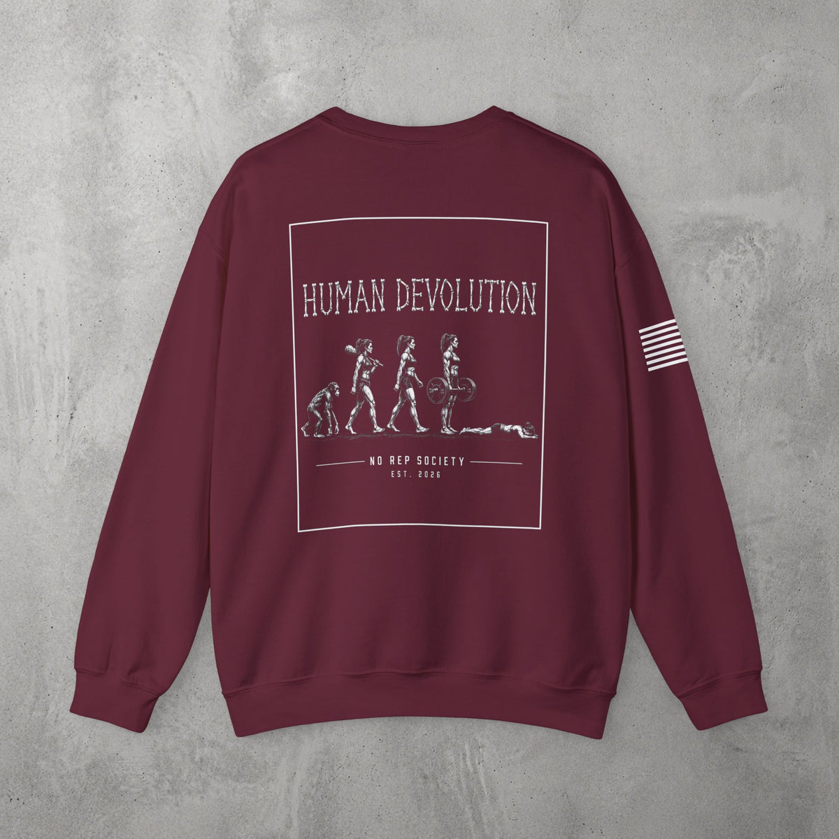 Maroon Human Devolution (WOMEN) Crewneck by The No Rep Society, flat lay on grey concrete, back print of evolution silhouettes ending face-down on the floor under HUMAN DEVOLUTION lettering.