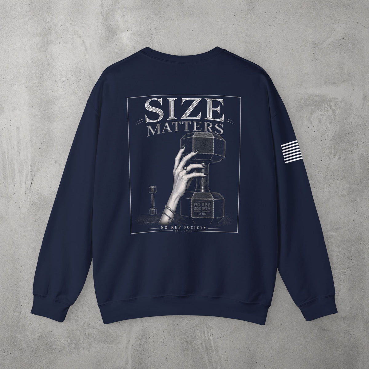 Navy Size Matters Crewneck by The No Rep Society, flat lay on grey concrete, back print of a hand gripping a large weight plate under SIZE MATTERS lettering.