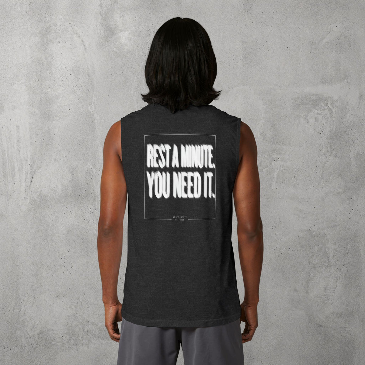 Dark Grey Heather Rest A Minute Muscle Tank worn by a female model, back view showing the Rest A Minute print.