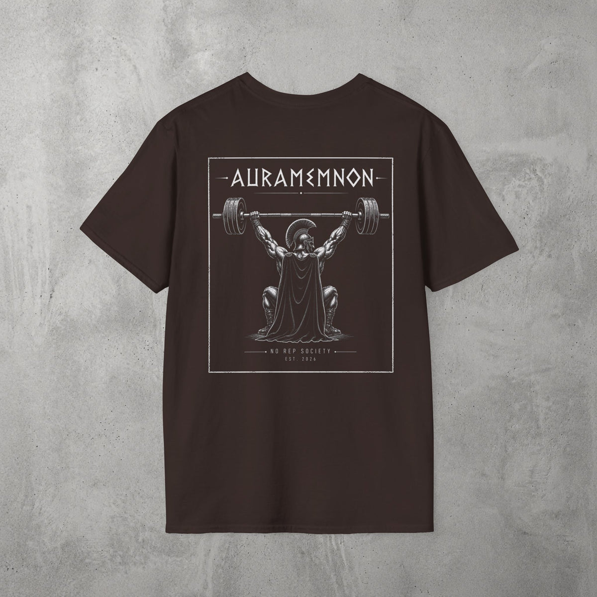 Dark Chocolate Auramemnon Tee by The No Rep Society, flat lay on grey concrete, back print of a caped warrior in a plumed helmet pressing a loaded barbell overhead under AURAMEMNON lettering.