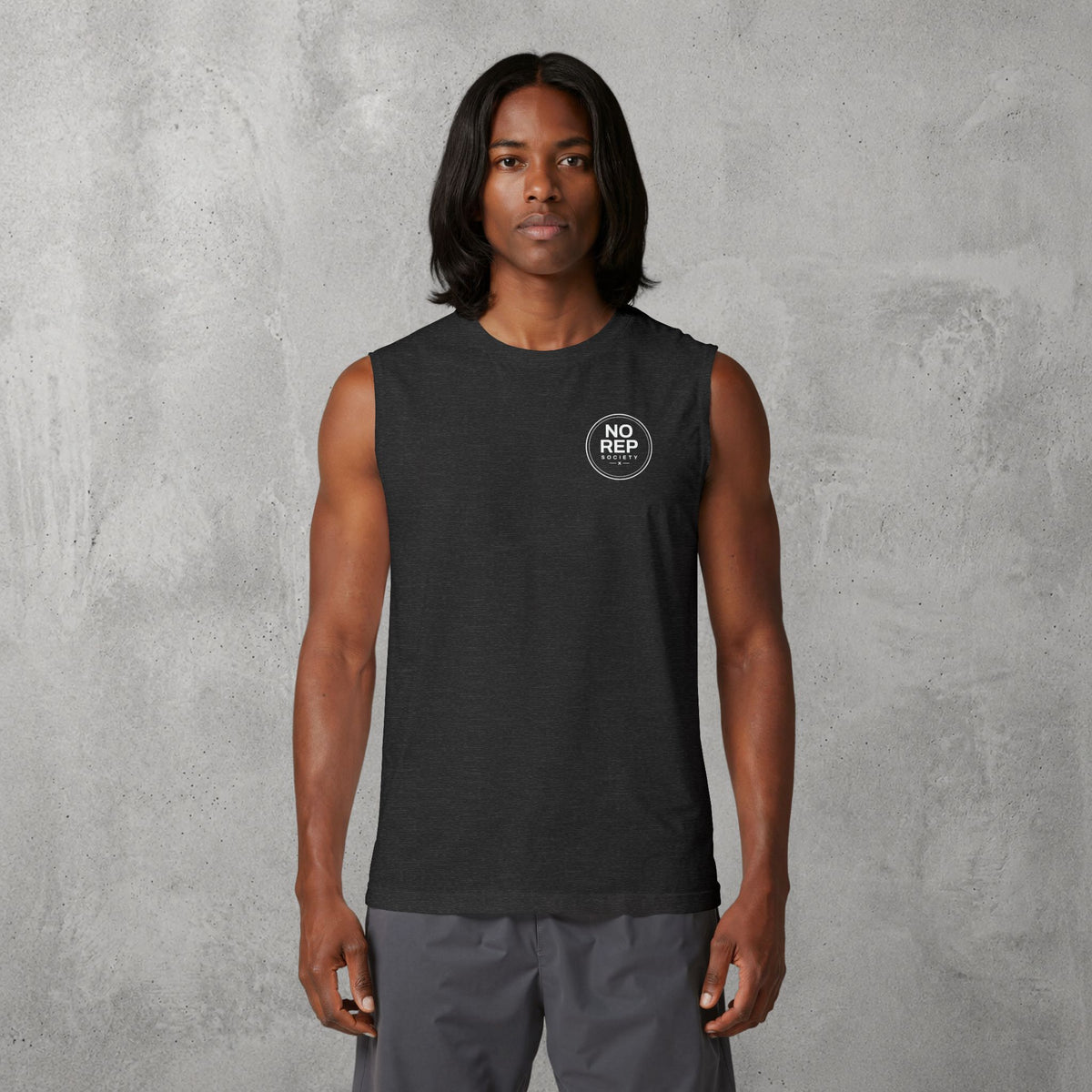 Model wearing the Dark Grey Heather NRS Clean Muscle Tank by The No Rep Society, minimal circular NO REP SOCIETY chest logo and no back print.