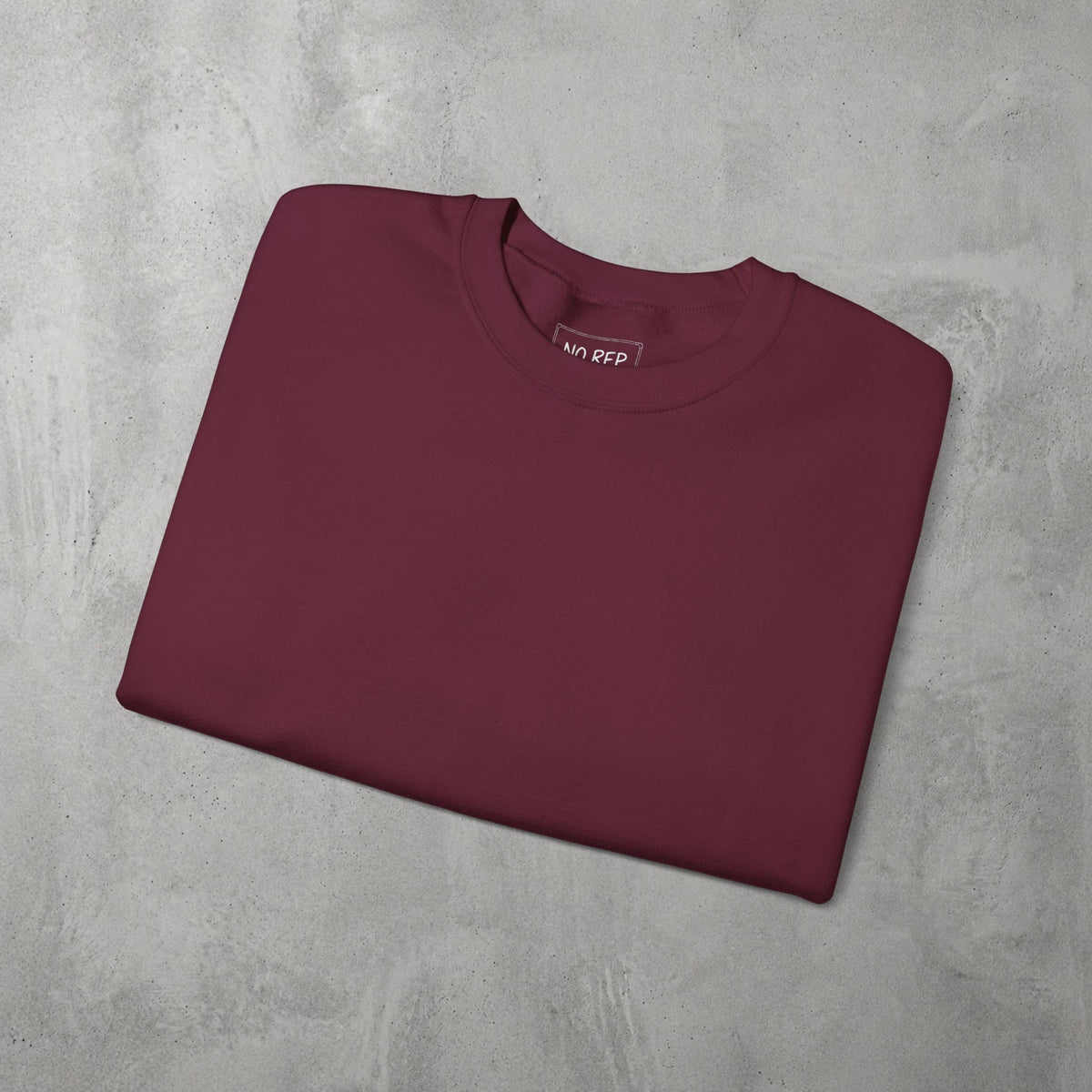 Maroon AMNRAP Crewneck by The No Rep Society, folded flat on grey concrete.