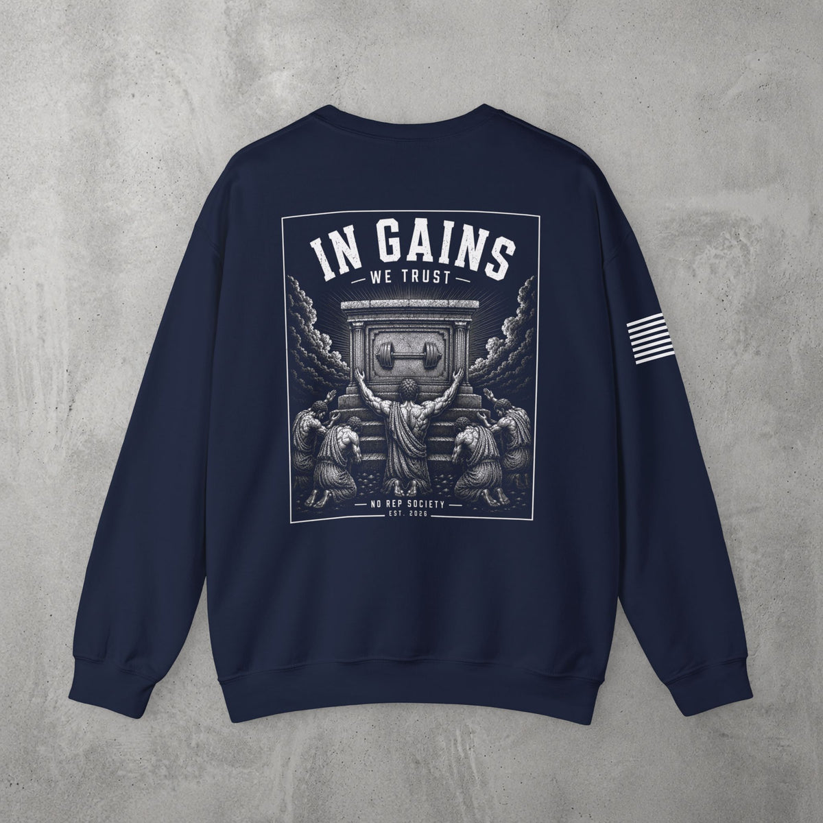 Navy In Gains We Trust Crewneck by The No Rep Society, flat lay on grey concrete, back print of an ornate temple facade with two kneeling figures and laurel branches under IN GAINS WE TRUST lettering.