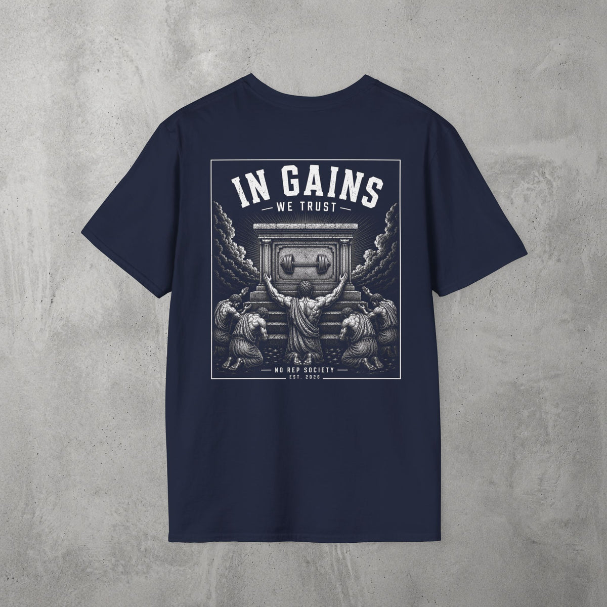 Navy In Gains We Trust Tee by The No Rep Society, flat lay on grey concrete, back print of an ornate temple facade with two kneeling figures and laurel branches under IN GAINS WE TRUST lettering.