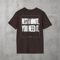 Dark Chocolate Rest A Minute Tee by The No Rep Society, flat lay on grey concrete, back print of REST A MINUTE. YOU NEED IT. in bold blurred capitals inside a thin frame.