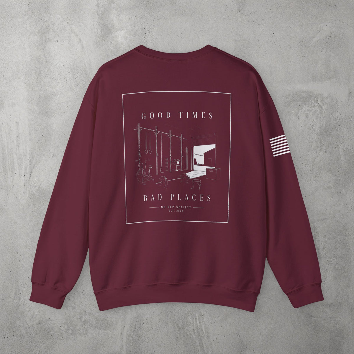 Maroon Good Times, Bad Places Crewneck by The No Rep Society, flat lay on grey concrete, back print of a rowing machine in fine line art between GOOD TIMES and BAD PLACES lettering.