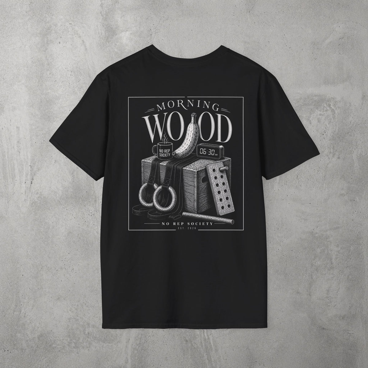 Black Morning Wood Tee by The No Rep Society, flat lay on grey concrete, back print of a banana, gymnastic rings and a wooden plyo box under MORNING WOOD lettering.