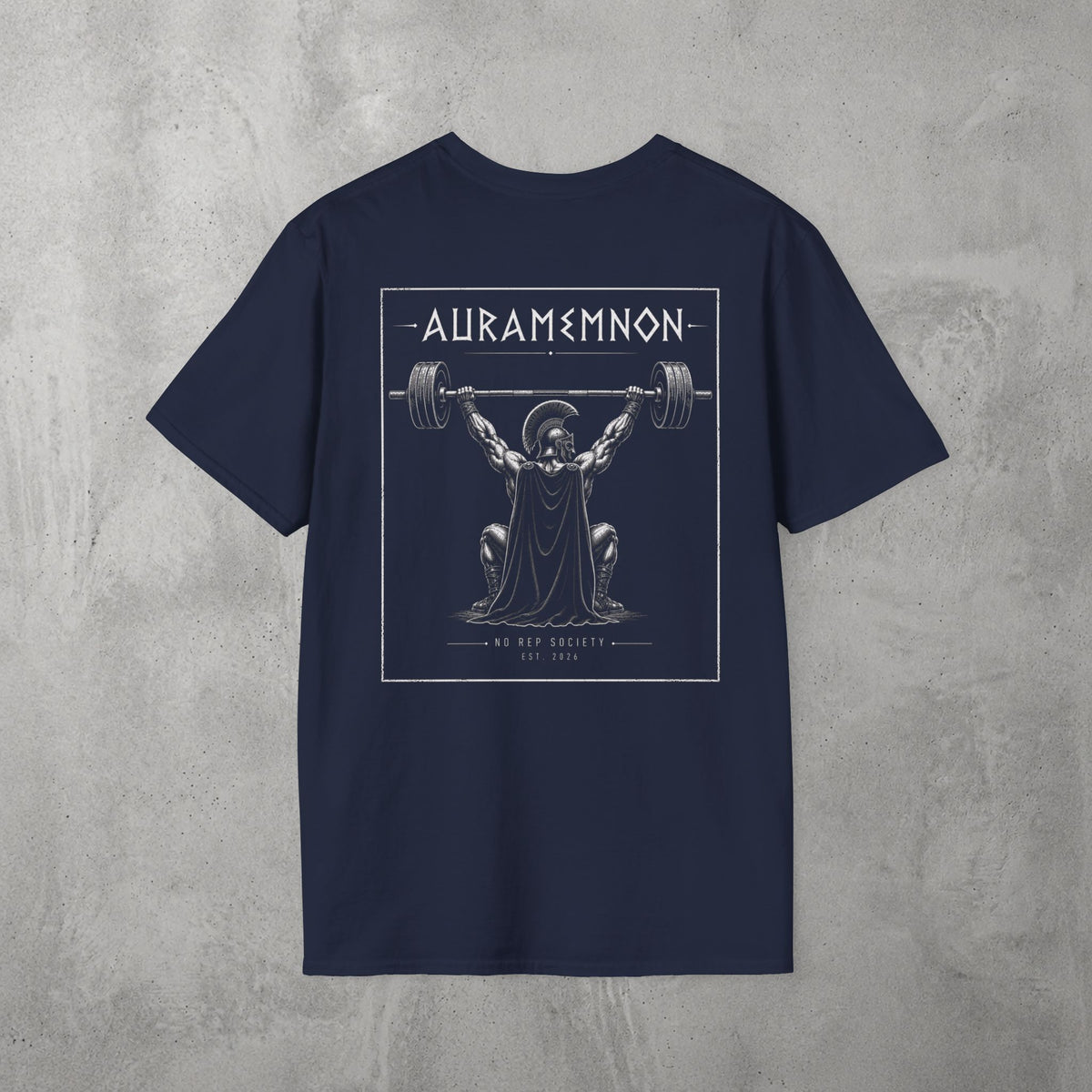 Navy Auramemnon Tee by The No Rep Society, flat lay on grey concrete, back print of a caped warrior in a plumed helmet pressing a loaded barbell overhead under AURAMEMNON lettering.