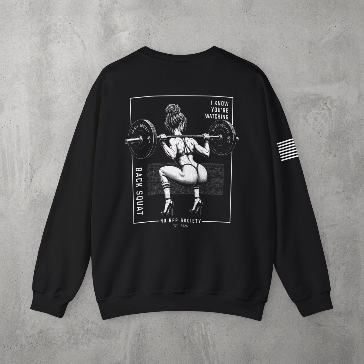 Black I Know You're Watching Crewneck by The No Rep Society, flat lay on grey concrete, back print of a woman mid back-squat inside a bordered frame under I KNOW YOU'RE WATCHING lettering.
