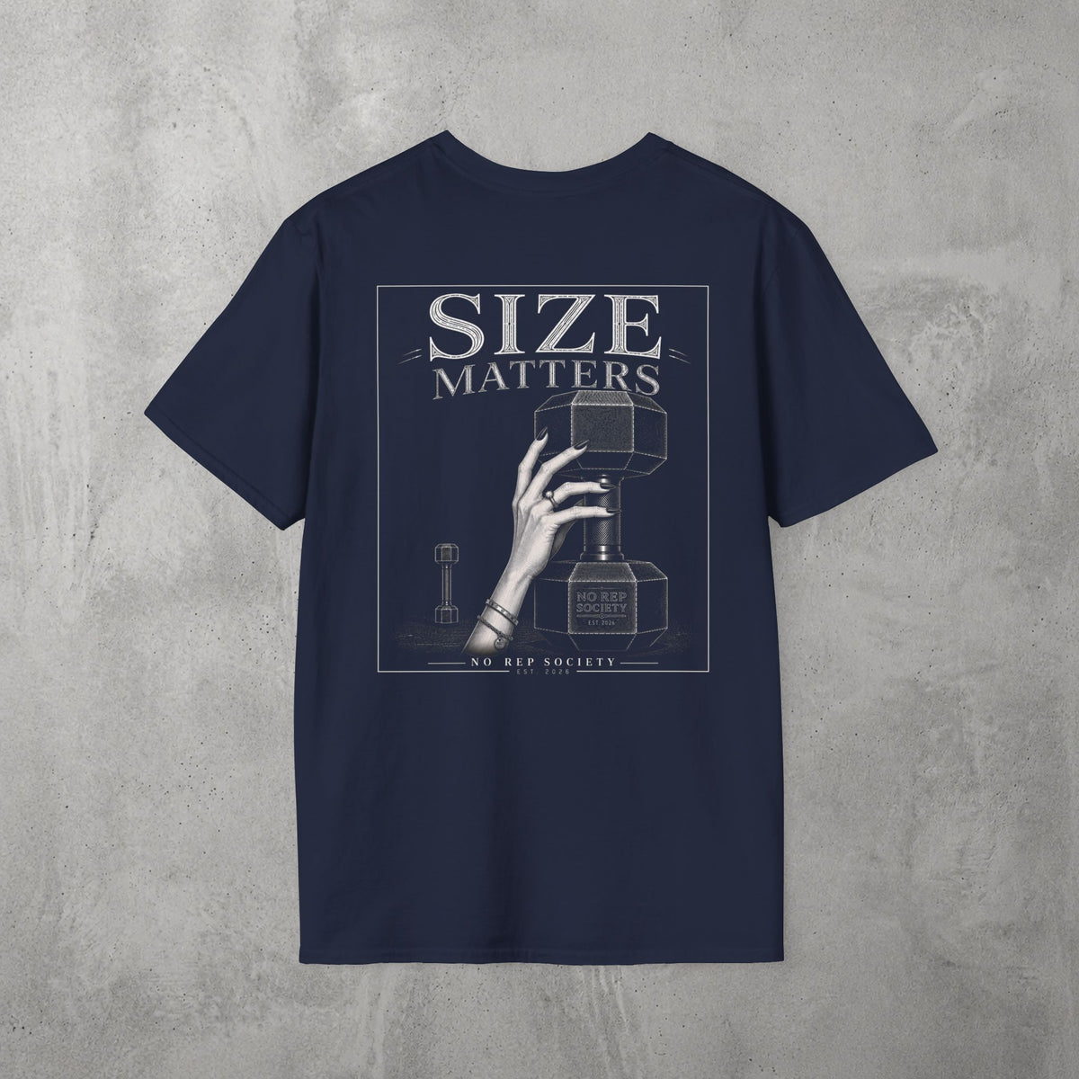 Navy Size Matters Tee by The No Rep Society, flat lay on grey concrete, back print of a hand gripping a large weight plate under SIZE MATTERS lettering.