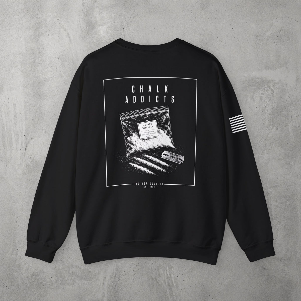 Black Chalk Addicts Crewneck by The No Rep Society, flat lay on grey concrete, back print of an open bag of gym chalk spilling across a bordered frame under CHALK ADDICTS lettering.