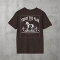 Dark Chocolate Trust The Plan Tee by The No Rep Society, flat lay on grey concrete, back print of the Trojan Horse with figures around it under TRUST THE PLAN lettering.