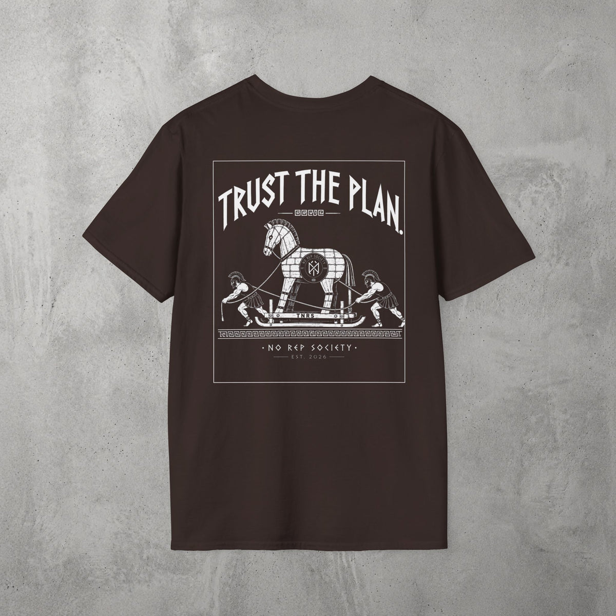 Dark Chocolate Trust The Plan Tee by The No Rep Society, flat lay on grey concrete, back print of the Trojan Horse with figures around it under TRUST THE PLAN lettering.