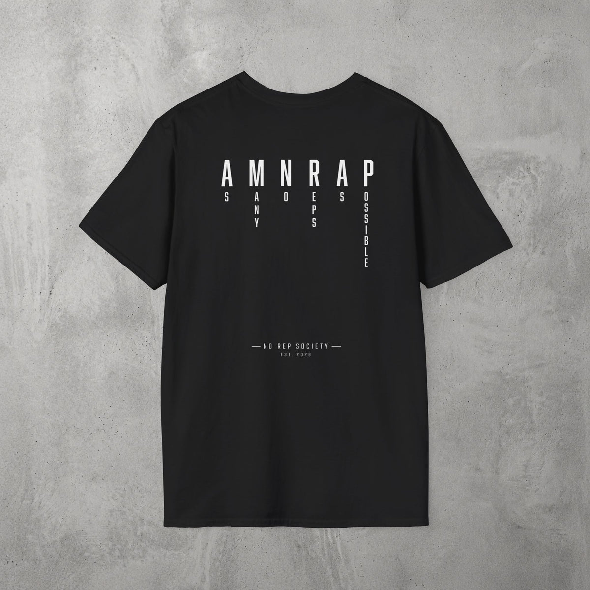 Black AMNRAP Tee by The No Rep Society, flat lay on grey concrete, back print of AMNRAP in wide spaced capitals with AS MANY NO-REPS AS POSSIBLE set vertically between the letters.