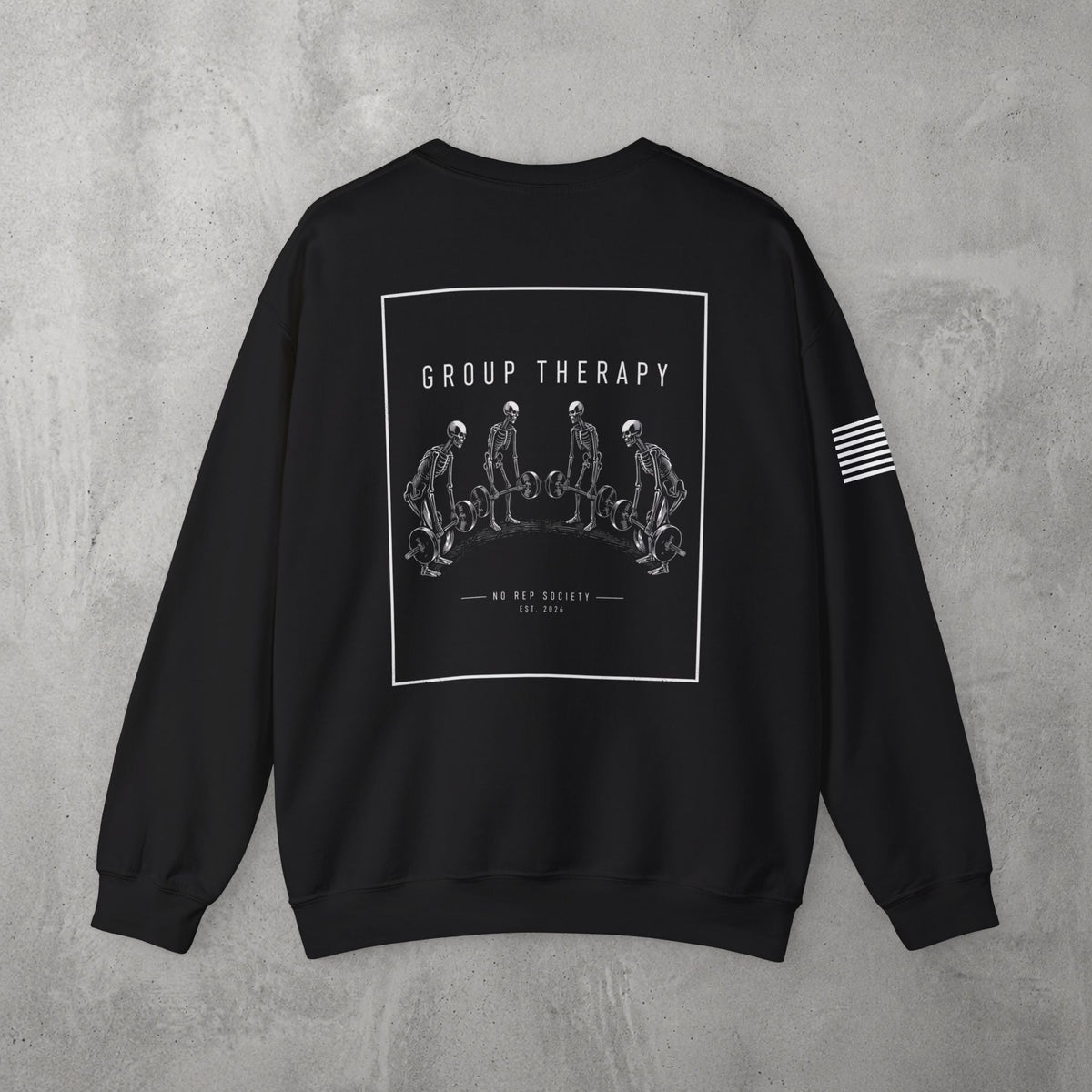 Black Group Therapy Crewneck by The No Rep Society, flat lay on grey concrete, back print of a circle of exhausted figures collapsed on the floor under GROUP THERAPY lettering.