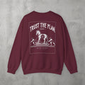 Maroon Trust The Plan Crewneck by The No Rep Society, flat lay on grey concrete, back print of the Trojan Horse with figures around it under TRUST THE PLAN lettering.
