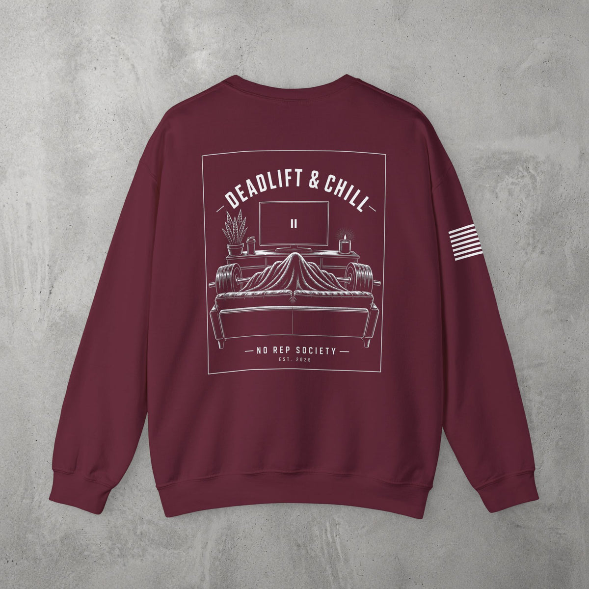 Maroon Deadlift & Chill Crewneck by The No Rep Society, flat lay on grey concrete, back print of a bed and television drawn in fine line art under DEADLIFT & CHILL lettering.