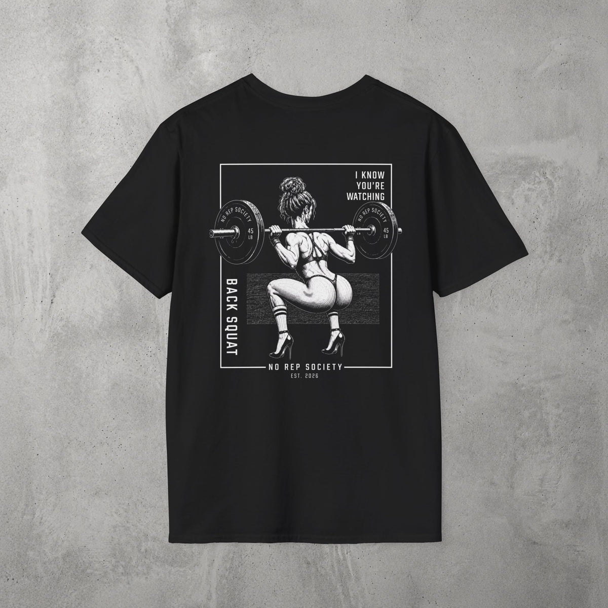 Black I Know You're Watching Tee by The No Rep Society, flat lay on grey concrete, back print of a woman mid back-squat inside a bordered frame under I KNOW YOU'RE WATCHING lettering.