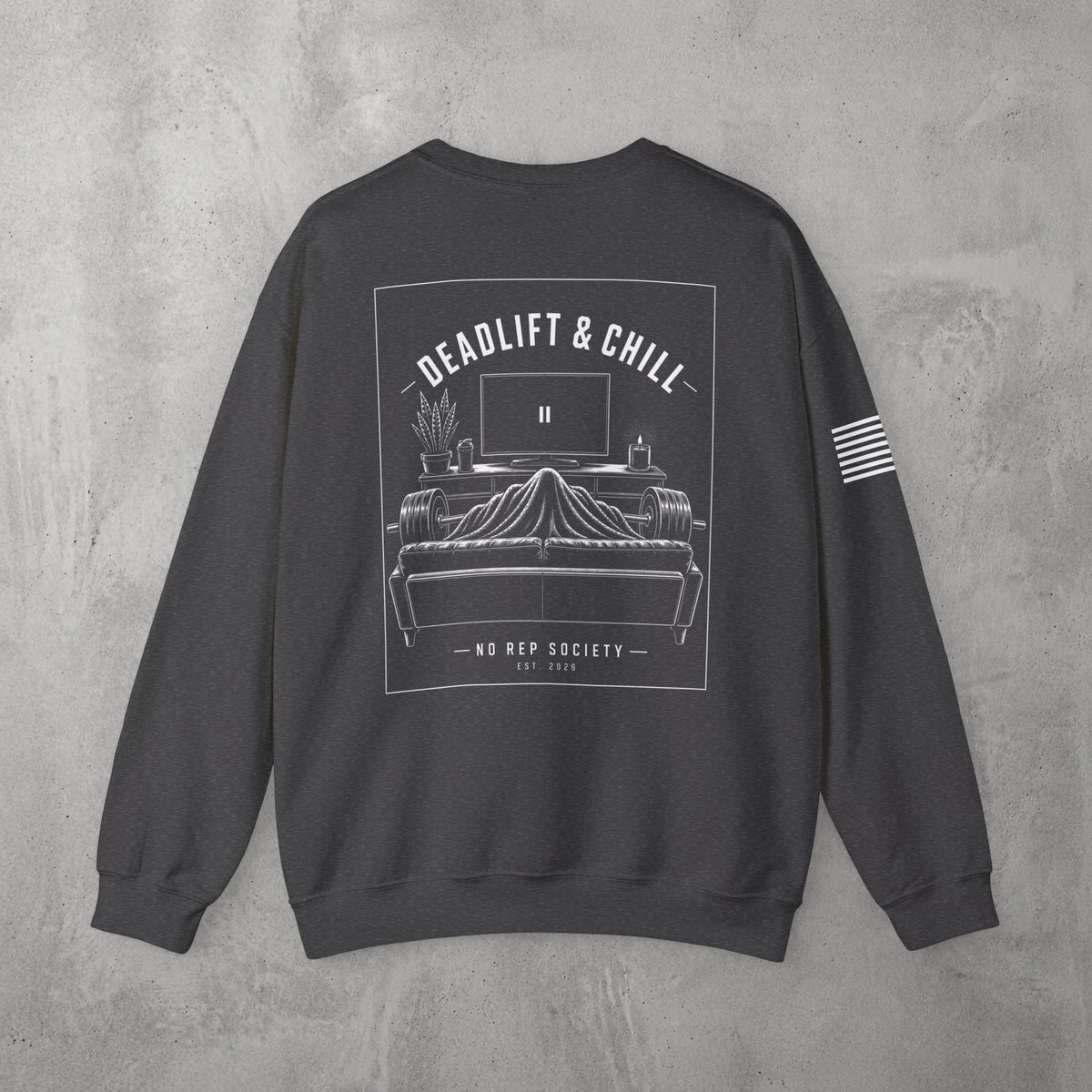 Dark Heather Deadlift & Chill Crewneck by The No Rep Society, flat lay on grey concrete, back print of a bed and television drawn in fine line art under DEADLIFT & CHILL lettering.