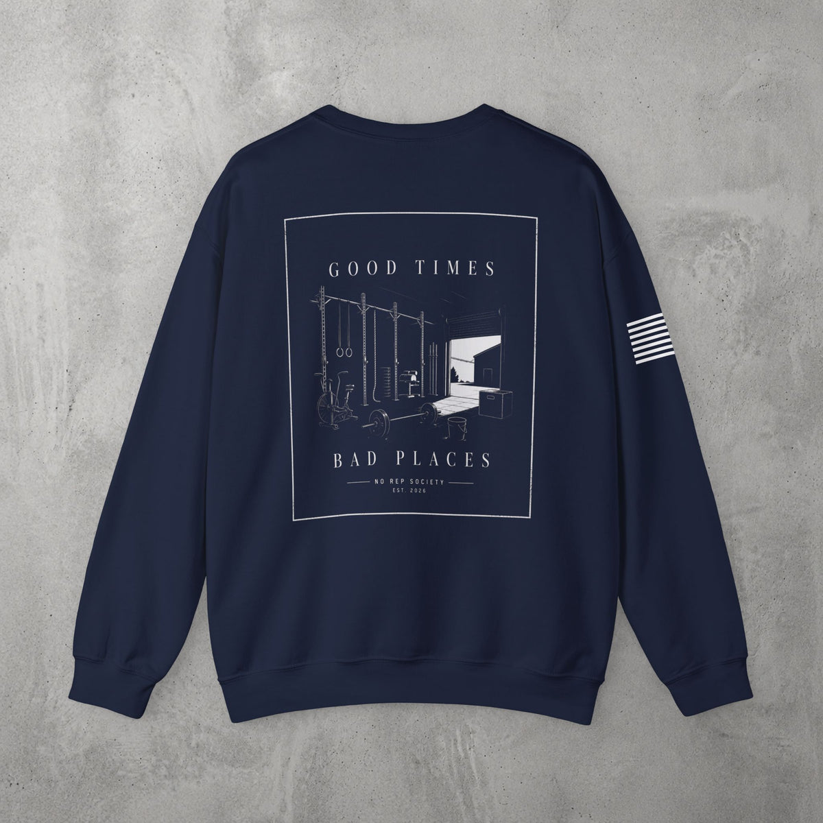 Navy Good Times, Bad Places Crewneck by The No Rep Society, flat lay on grey concrete, back print of a rowing machine in fine line art between GOOD TIMES and BAD PLACES lettering.