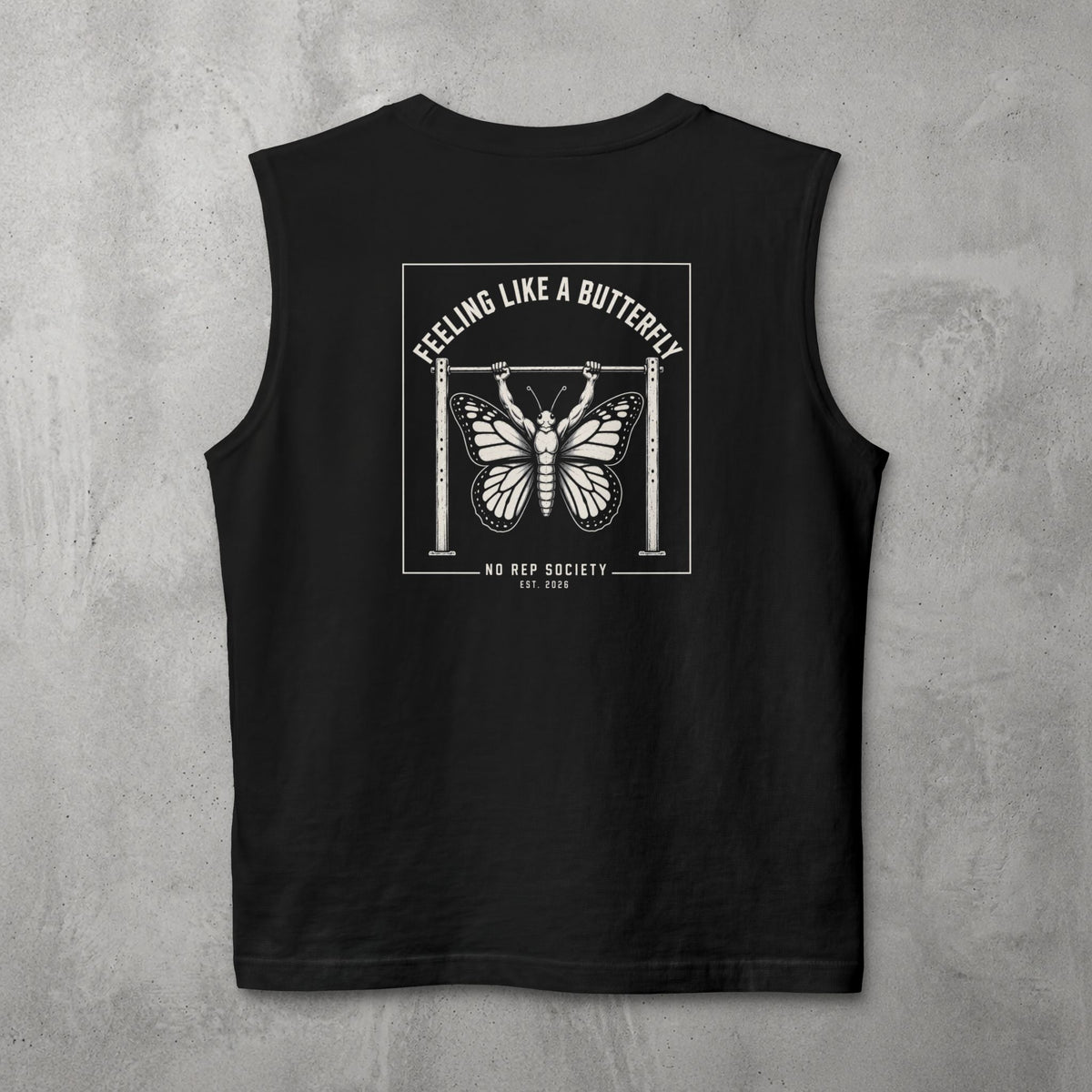Black Feeling Like A Butterfly Muscle Tank by The No Rep Society, flat lay on grey concrete, back print of a moth with spread wings hanging between two rig uprights under FEELING LIKE A BUTTERFLY lettering.