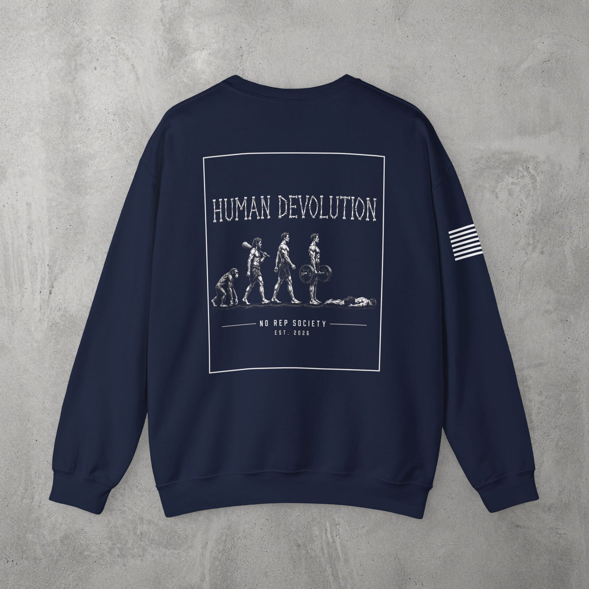 Navy Human Devolution (MEN) Crewneck by The No Rep Society, flat lay on grey concrete, back print of evolution-of-man silhouettes ending face-down on the floor under HUMAN DEVOLUTION lettering.