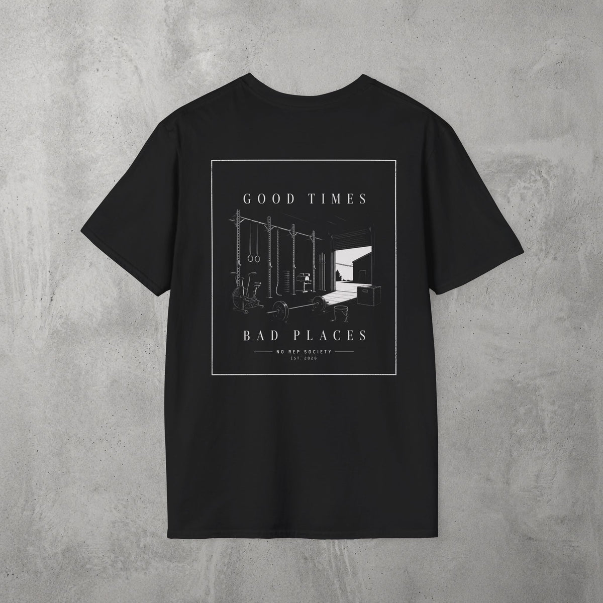 Black Good Times, Bad Places Tee by The No Rep Society, flat lay on grey concrete, back print of a rowing machine in fine line art between GOOD TIMES and BAD PLACES lettering.