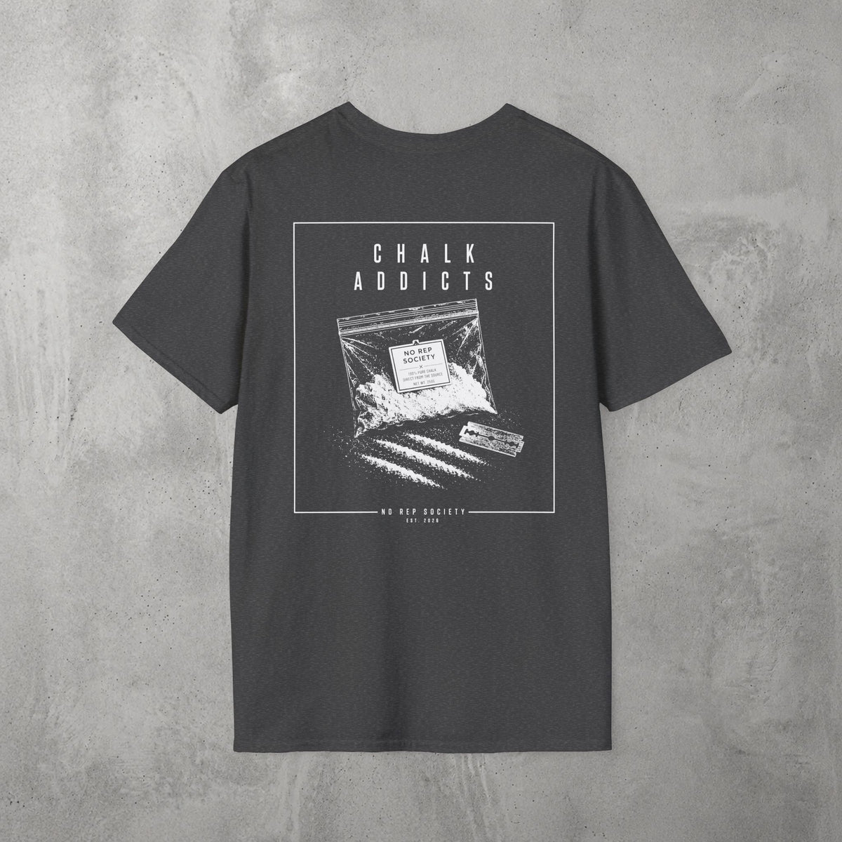 Dark Heather Chalk Addicts Tee by The No Rep Society, flat lay on grey concrete, back print of an open bag of gym chalk spilling across a bordered frame under CHALK ADDICTS lettering.