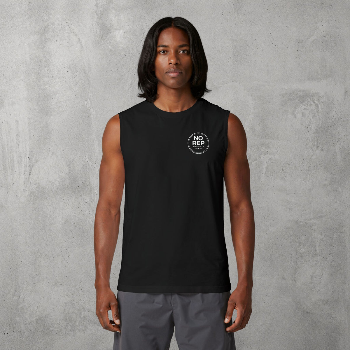 Model wearing the Black NRS Clean Muscle Tank by The No Rep Society, minimal circular NO REP SOCIETY chest logo and no back print.
