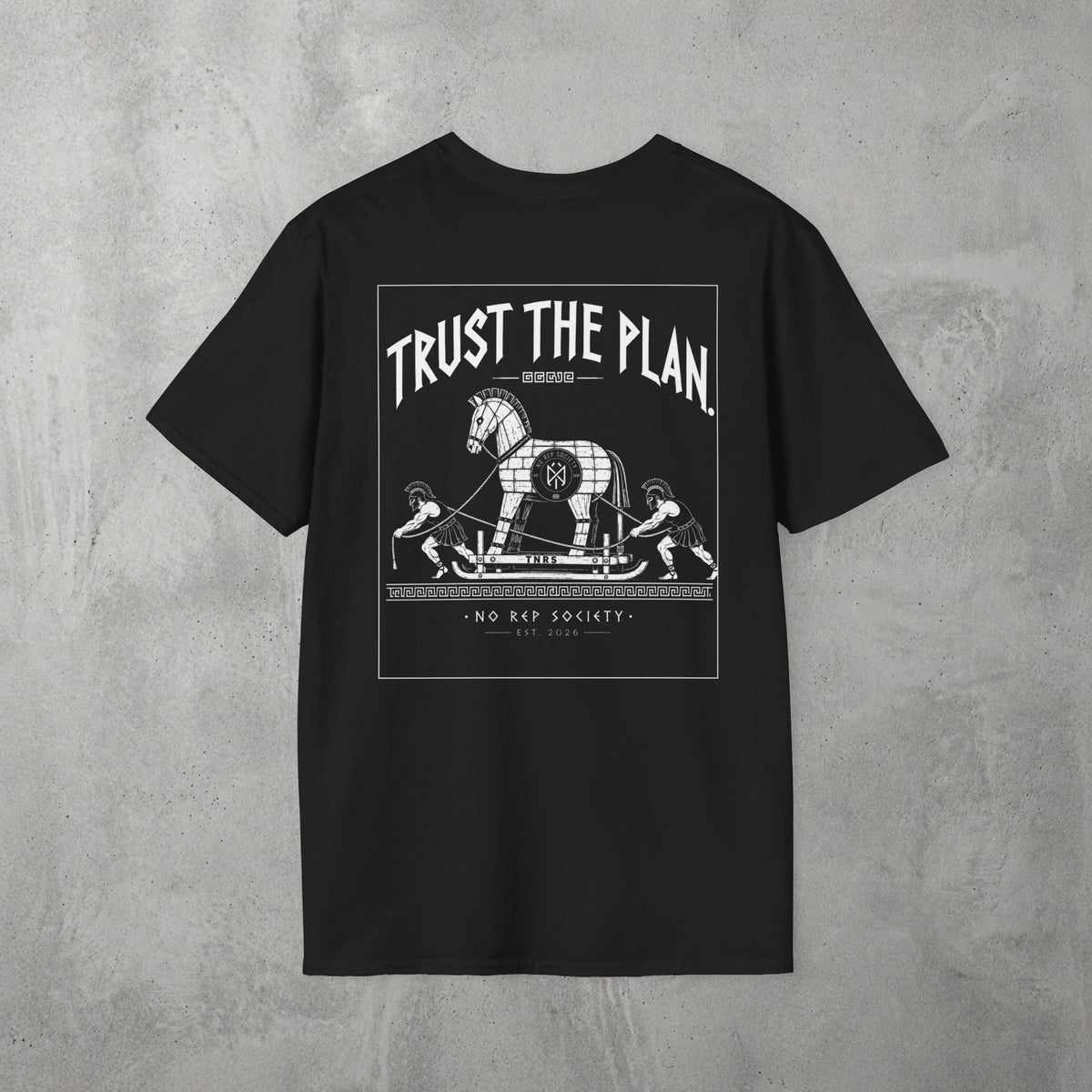 Black Trust The Plan Tee by The No Rep Society, flat lay on grey concrete, back print of the Trojan Horse with figures around it under TRUST THE PLAN lettering.