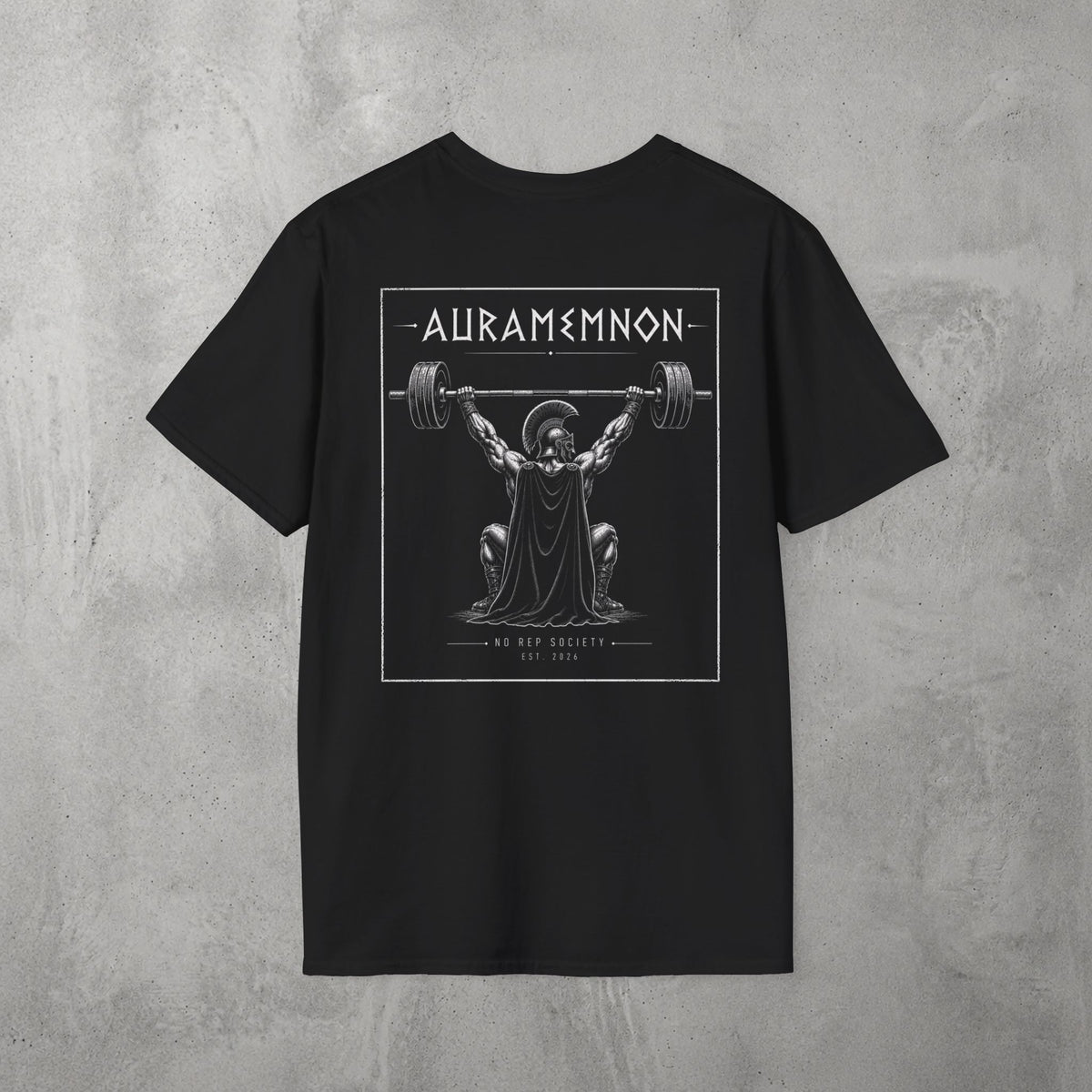 Black Auramemnon Tee by The No Rep Society, flat lay on grey concrete, back print of a caped warrior in a plumed helmet pressing a loaded barbell overhead under AURAMEMNON lettering.