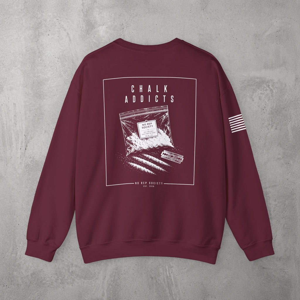 Maroon Chalk Addicts Crewneck by The No Rep Society, flat lay on grey concrete, back print of an open bag of gym chalk spilling across a bordered frame under CHALK ADDICTS lettering.