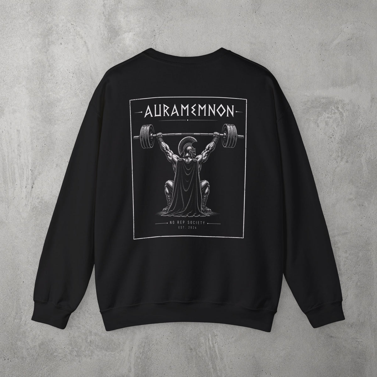 Black Auramemnon Crewneck by The No Rep Society, flat lay on grey concrete, back print of a caped warrior in a plumed helmet pressing a loaded barbell overhead under AURAMEMNON lettering.
