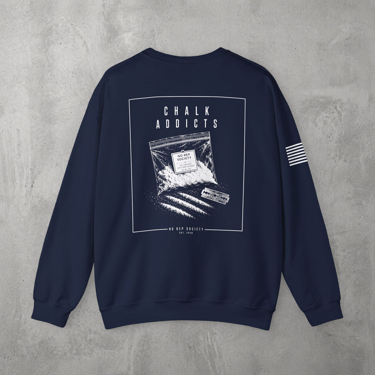 Navy Chalk Addicts Crewneck by The No Rep Society, flat lay on grey concrete, back print of an open bag of gym chalk spilling across a bordered frame under CHALK ADDICTS lettering.