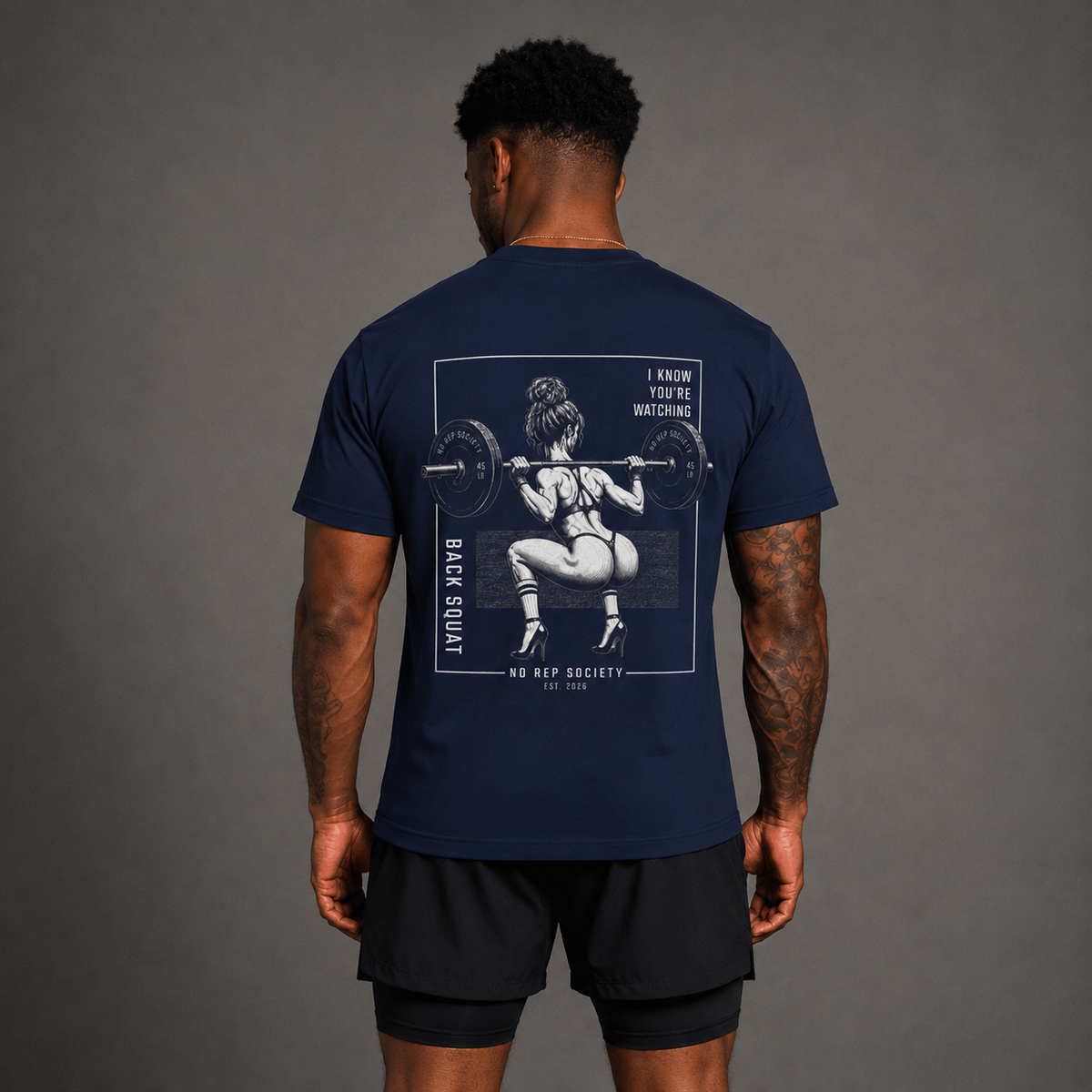 Navy I Know You're Watching Tee by The No Rep Society, worn by a male model, back view showing the I KNOW YOU'RE WATCHING print.