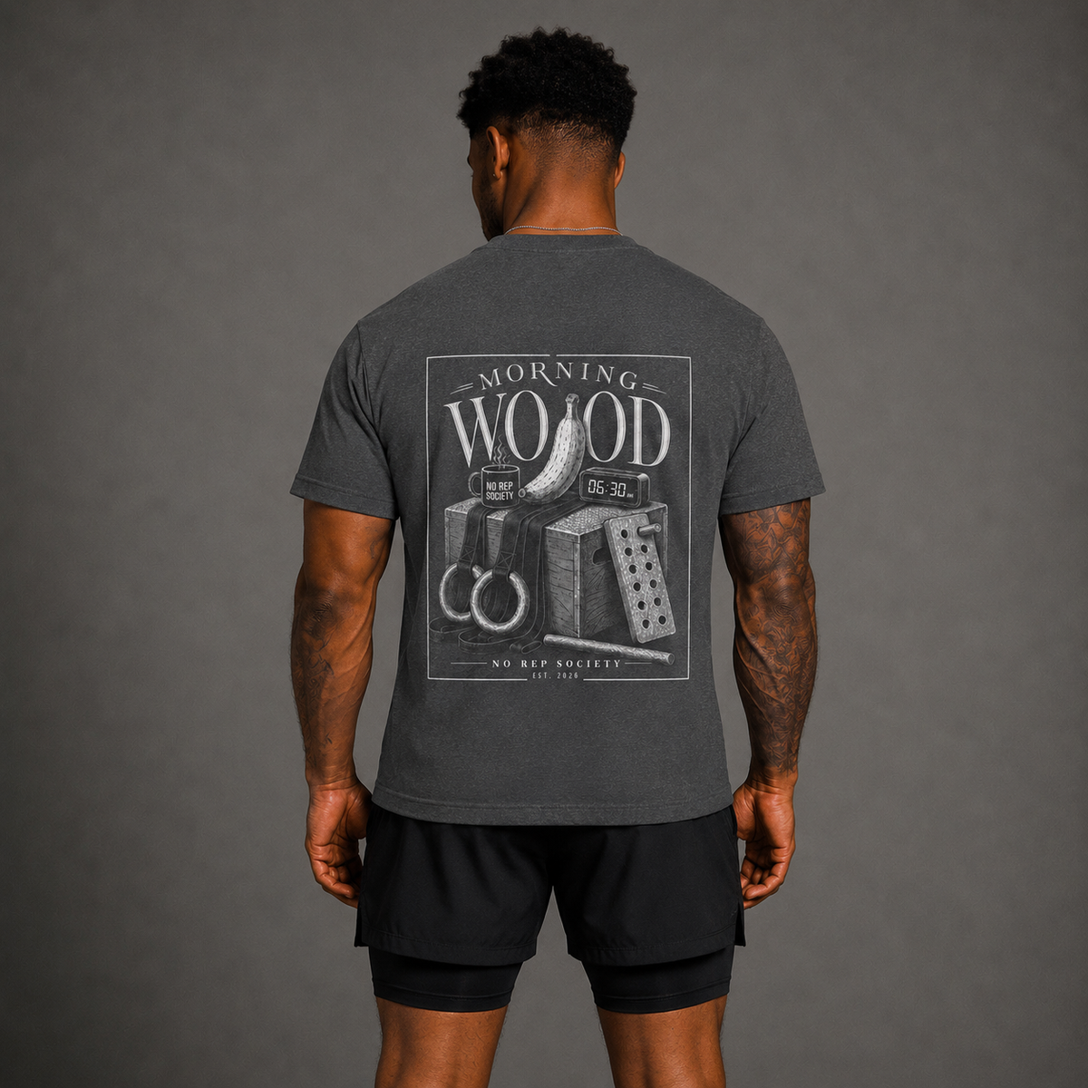 Dark Heather Morning Wood Tee by The No Rep Society, worn by a male model, back view showing the MORNING WOOD print.