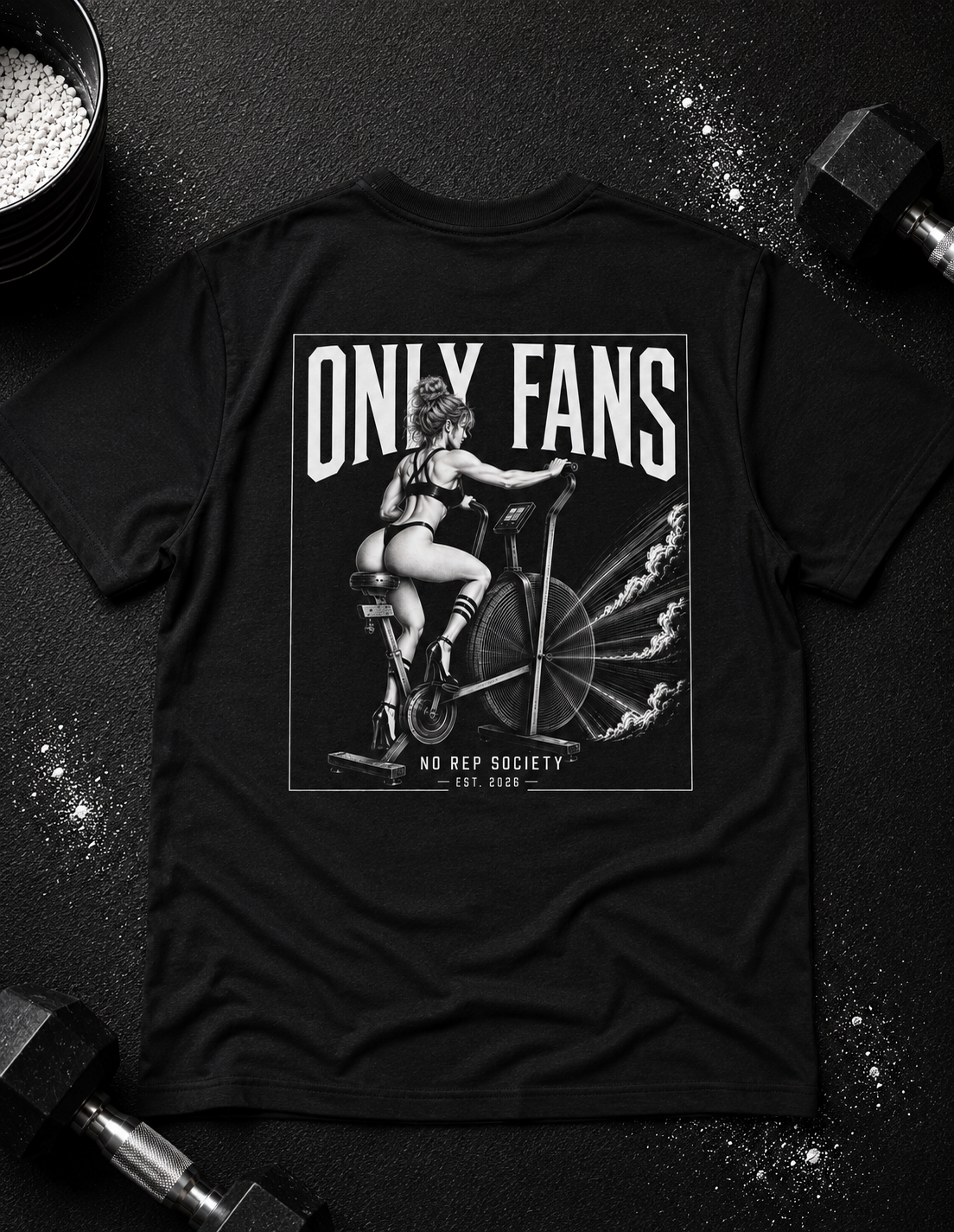 Black Only Fans Tee by The No Rep Society, laid flat on a dark gym floor between a chalk bucket and dumbbells, back print of a pin-up figure seated on a large industrial fan inside a bordered frame under ONLY FANS lettering.