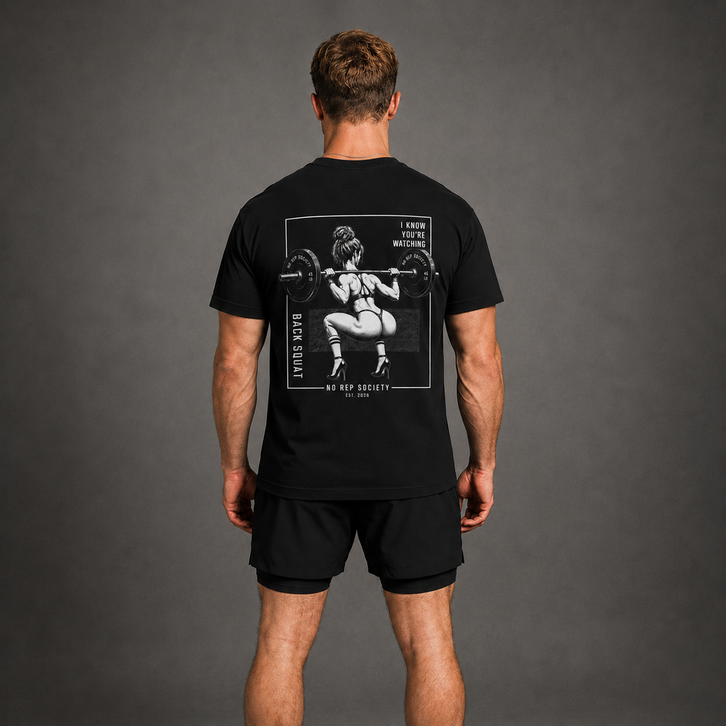 Black I Know You're Watching Tee by The No Rep Society, worn by a male model, back view showing the I KNOW YOU'RE WATCHING print.